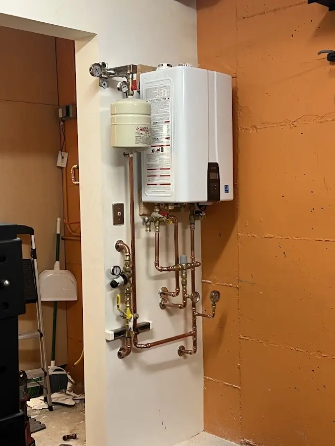 Plumbing technician inspecting water heater connections in Center